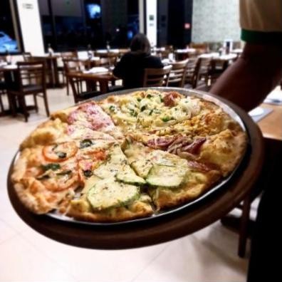 Garçom servindo pizza de quatro sabores no salão