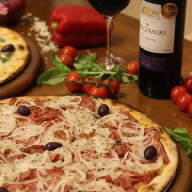 Pizza de calabresa servida com vinho e tomates