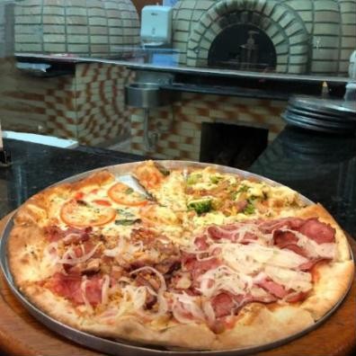 Pizza de quatro sabores em frente ao forno a lenha
